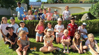 Die Kinder präsentieren stolz die gebastelten Gartenfackeln im Garten der evangelischen Kirche (Bild: Caro Dörner)