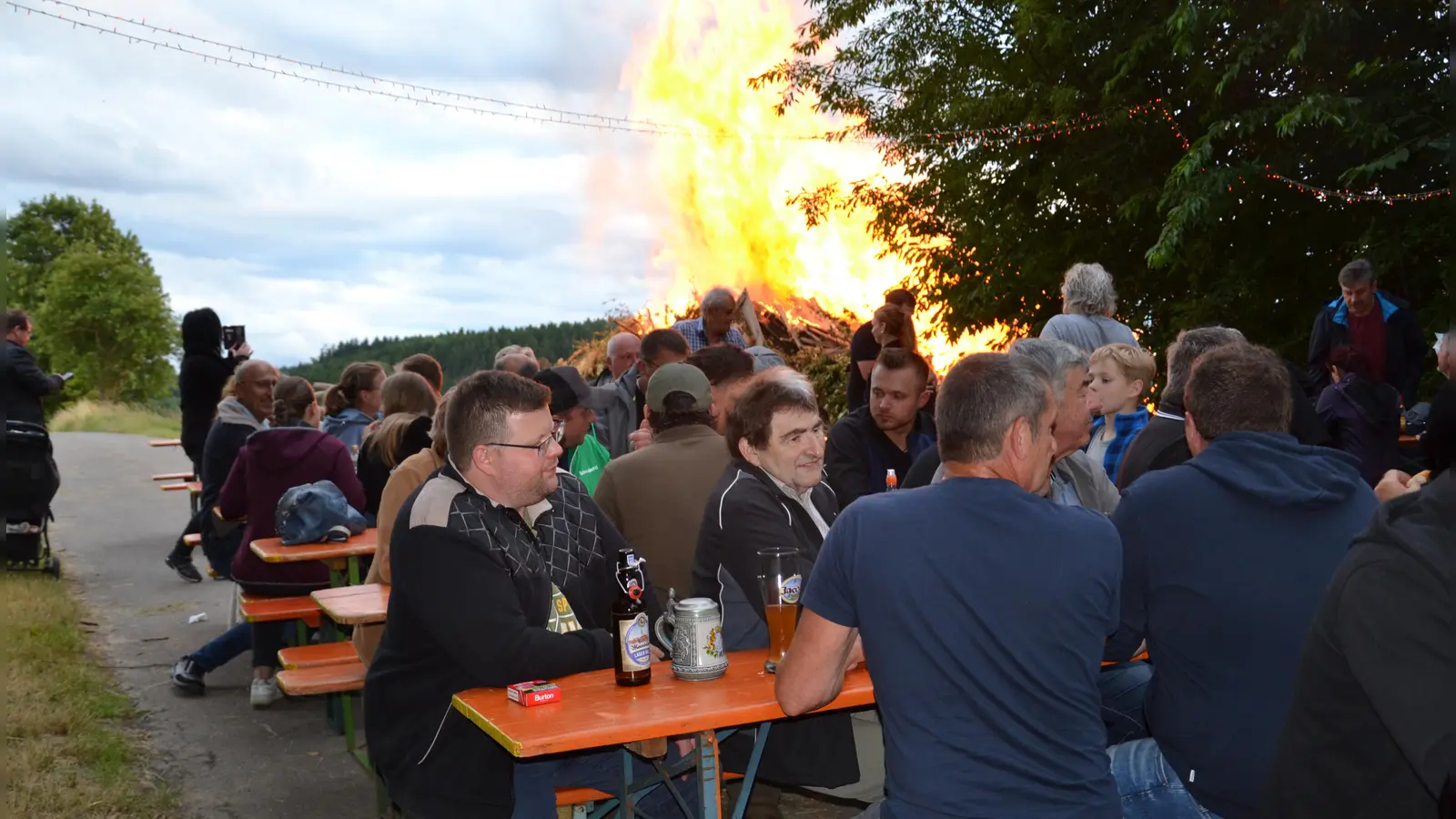 In einem großen Abstand konnten die Besucher dem Abbrennen des Johannisfeuers im Hintergrund zuschauen. (Bild: Peter Garreiss)