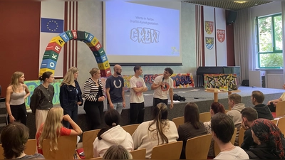 Schülerinnen und Schüler präsentieren ihre Werte-Graffitis, die sie in einem Workshop unter Anleitung des Sprayers StepperOne angefertigt haben.  (Bild: Lena Altmann)