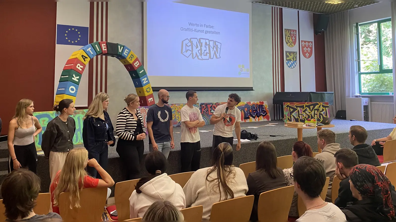 Schülerinnen und Schüler präsentieren ihre Werte-Graffitis, die sie in einem Workshop unter Anleitung des Sprayers StepperOne angefertigt haben.  (Bild: Lena Altmann)