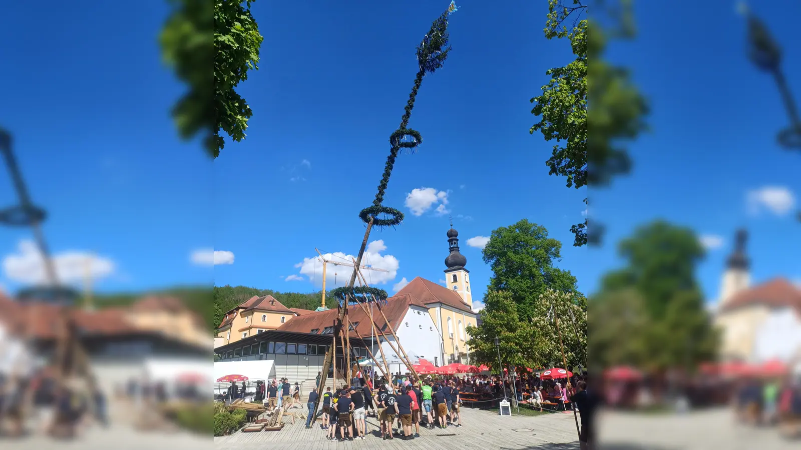 Zahlreiche Helfer stellten mit viel Muskelkraft bei herrlichstem Wetter den Maibaum auf dem Dorfplatz in Wolfring auf.  (Bild: Franz Ziegelmeier)