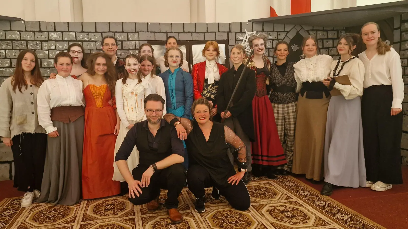 Schultheatergruppe zur Aufführung von „Dracula“: Auf dem Bild sind Julia Brandl als Dracula (Fünfte von rechts), Josefine Slany als sein Gegenspieler Van Helsing (Sechster von rechts), Annika Keil als Dr. Seward (Siebte von rechts) und Hanna Neumann in der Rolle der Mrs. Hawkins (Dritte von rechts); vorne von rechts Frau Regler und Herr Max. (Bild: Kerstin Reiter)