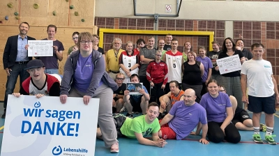 Gelungene Überraschung beim Freitagstraining: Sabrina Feige (3.v.r.) von der IG Metall Amberg und Lars Roder (2.v.l.) von der Grammer AG überreichten dem Freizeitclub der Lebenshilfe Amberg-Sulzbach symbolische Schecks in Höhe von 1.295 Euro für die Finanzierung künftiger Wettkämpfe. (Bild: Sophie Butz)