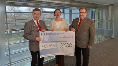 Leiter Bernhard Meiler (links) und Hans Gruber von der Blaskapelle Oberwildenau überreichten Viola Vogelsang-Reichl, Vorsitzende von „Lichtblicke“, den aufgestockten Erlös aus dem Jubiläumskonzert. (Bild: Stephanie Hladik)