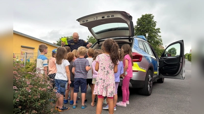 Ein Beamter der Polizei Vohenstrauß zeigt den Kindern die Ausrüstung und das Fahrzeug. (Bild: Verena Gawel)