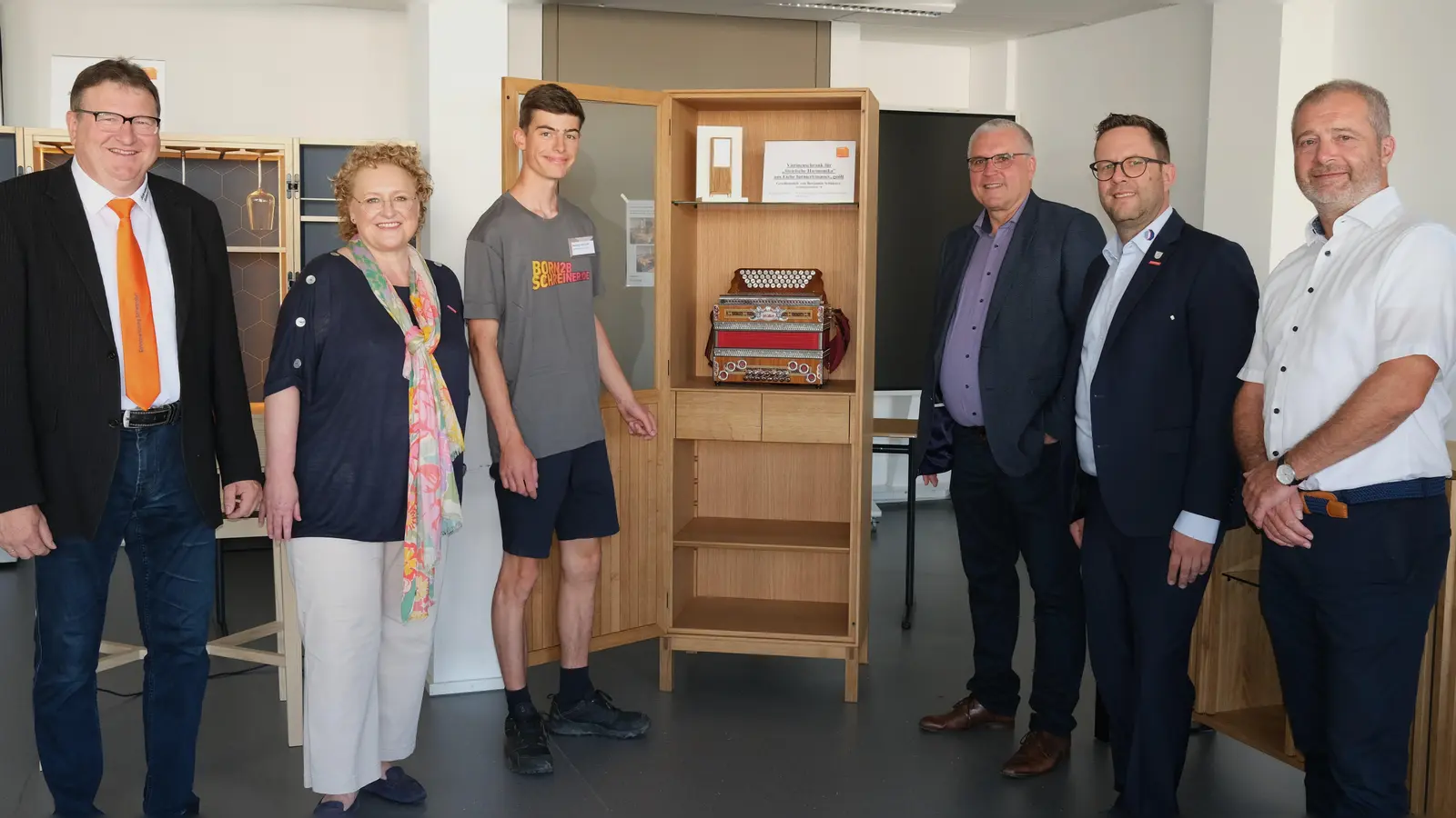 Absolvent Benjamin Schuierer (Dritter von links) hatte als Gesellenstück eine Vitrine für seine „Steirische Harmonika“ gefertigt und bekam dafür ein Kompliment von Obermeister Werner Schönberger, Claudia Mendel von der Kreishandwerkerschaft, vom stellvertretenden Landrat Richard Tischler, Kreishandwerksmeister Florian Danzl und dem städtischen Vertreter Armin Rank (von links).  (Bild: Rudi Hirsch )