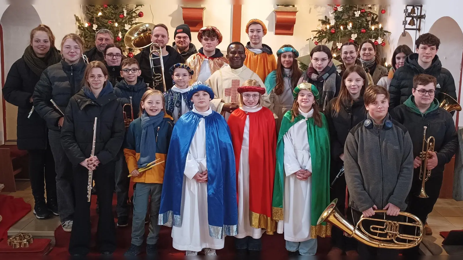 Gruppenfoto der Kemnather Jugendblaskapelle zusammen mit den Sternsingern, sowie Pfarrvikar Dr. Linus zur Dreikönigsmesse in der Herz-Jesu-Pfarrei. (Bild: Roman Melzner)
