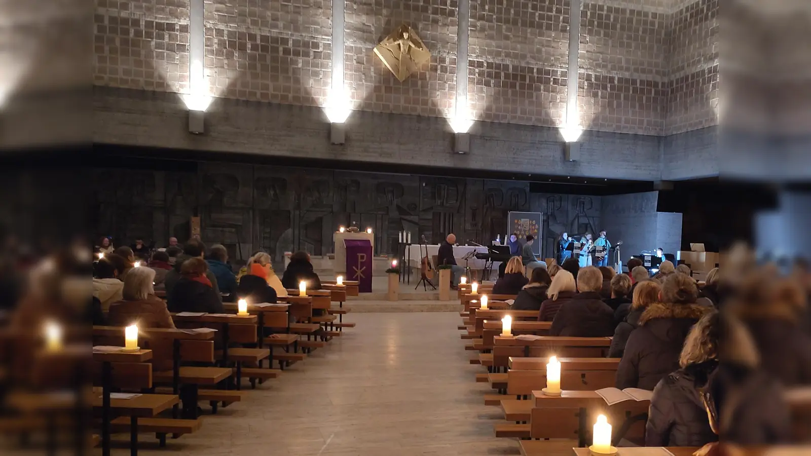 Der stimmungsvoll beleuchtete Kirchenraum mit Blick auf die drei Musikgruppen. (Bild: Patrick Hummer)
