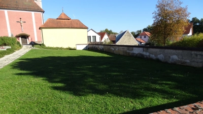 Auf dieser Rasenfläche soll das Urnenfeld entstehen. Die marode Mauer zum Parkplatz hin wird dann beseitigt. (Bild: Markus Müller)