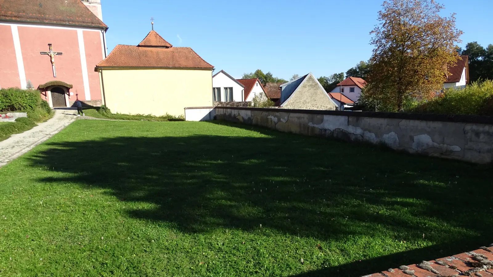 Auf dieser Rasenfläche soll das Urnenfeld entstehen. Die marode Mauer zum Parkplatz hin wird dann beseitigt. (Bild: Markus Müller)