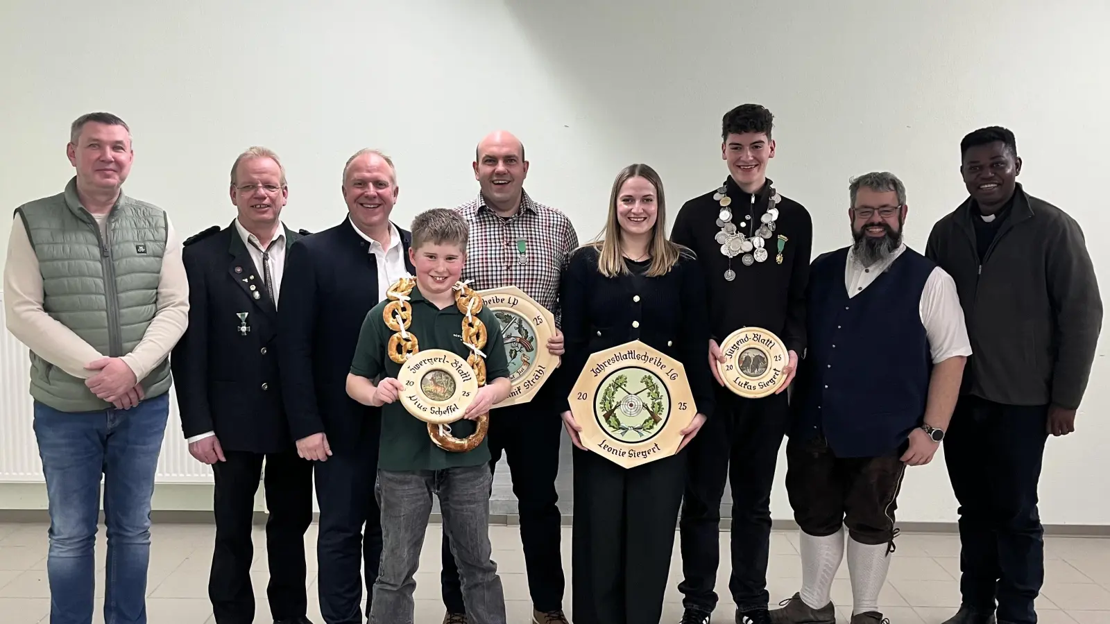 Zeigt die Jahresblattl Sieger von links: 2. Vorsitzenden Heiko Friedrichs, Gauschützenmeister Klaus Ketzler, 1. Bgm Marcus Eichenmüller, Zwergal Pius Scheffel, Luftpistole Dominik Strähl, Luftgewehr Leonie Siegert, Jugend Lukas Siegert, Schützenmeister Florian Friedl, Pfarrvikar Ndudi. (Bild: Constanze Pausch)