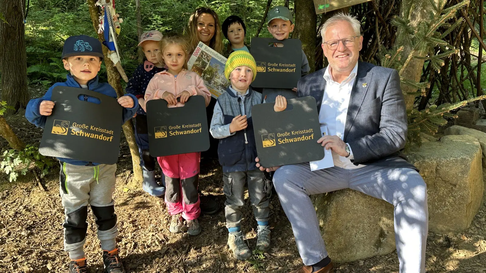 Die Kinder des Waldkindergartens „Schwanenkinder“ und Einrichtungsleitung Veronika Bauer (4. von links) freuten sich über den Besuch von Oberbürgermeister Feller (rechts) in ihrem „Zauberwald“<br> (Bild: Lara Schmaus)