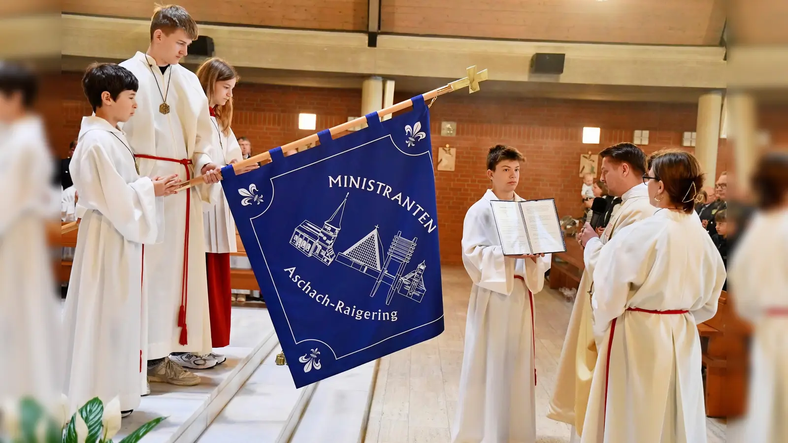 Die neue Ministrantenfahne der Pfarrei Aschach-Raigering, ein sichtbares Zeichen des Glaubens und der Verbundenheit, erhält ihre Weihe durch Kaplan Marvin Schwedler. (Bild: Alfred Schorner)