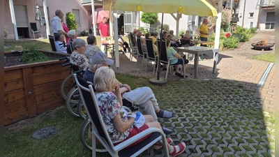 In einem besonderen Rahmen, nämlich verbunden mit einem Johannisfeuer, fand die Bewohnerversammlung des BRK-Seniorenheims St. Barbara statt. Nach dem Bericht des Beiratsvorsitzender Rudi Wild (stehend rechts) segnete Stadtpfarrer Johann Hofmann das Johannisfeuer. Rechts neben ihm (halb verdeckt). Heimleiterin Astrid Geitner. (Bild: Anita Dobmeier)