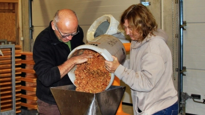 Udo Holweg und Marianne Badura kippen die gehäckselten Apfelstücke in die Saftpresse. (Bild: Leonhard Ehras)