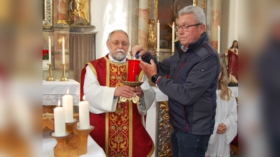 Pfarrer Alfons Forster (links) und Kirchenratsvorsitzender Helmut Ermer entzündeten das „Ewige Licht“ als Zeichen dafür, dass das Gotteshaus nach sieben Jahren Baustelle jetzt wieder für Messfeiern offen ist, dazu gab es den Segen mit Weihwasser.  (Bild: Albert Gruber)