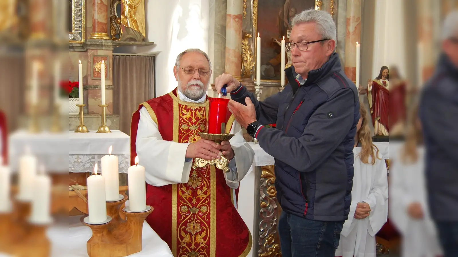 Pfarrer Alfons Forster (links) und Kirchenratsvorsitzender Helmut Ermer entzündeten das „Ewige Licht“ als Zeichen dafür, dass das Gotteshaus nach sieben Jahren Baustelle jetzt wieder für Messfeiern offen ist, dazu gab es den Segen mit Weihwasser.  (Bild: Albert Gruber)