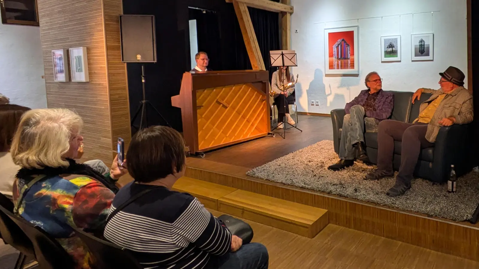 Bei der Vernissage im Kunsthaus Waldsassen – auf der Couch im lockeren Gespräch Bernhard Dagner und Stefan Voit (von links). Andreas Sagstetter (Klavier) und Lena Schwartling (Saxofon) begleiteten die Ausstellungseröffnung musikalisch.  (Bild: Paul Zrenner)