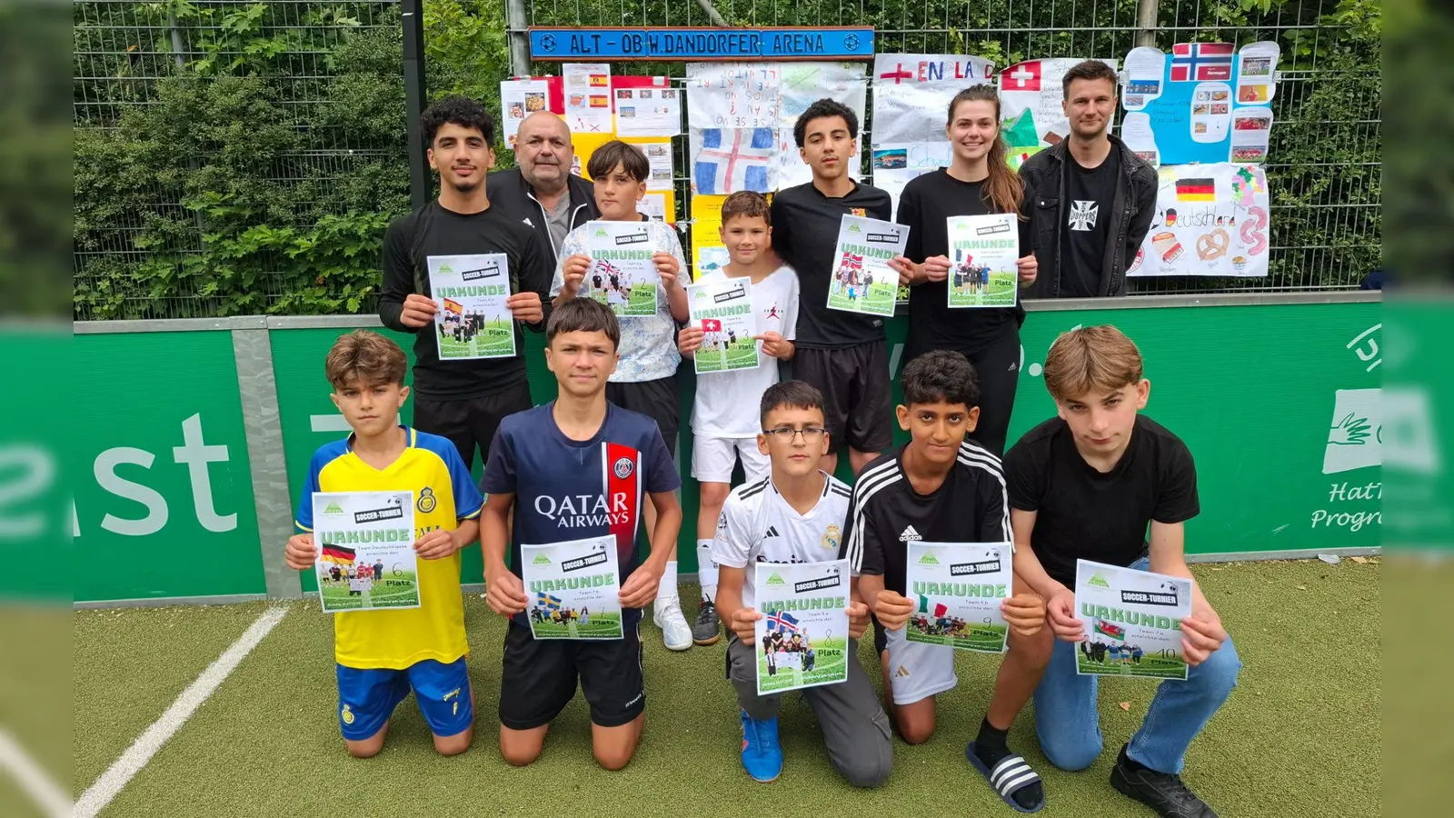 „Sport verbindet” - Dieses Jahr wurde von allen Klassen mit vielen Nationalitäten die Europameisterschaft der Frauen in der Schweiz nachgespielt; die Klassenvertreter je nach Platzierung stellten sich zum Siegerfoto auf: v.l. stehend 1.Spanien (8b) 2.England (6a) 3.Schweiz (6b) 4.Norwegen (8a) 5.Frankreich (Lehrerteam-Fr. Engelhardt), kniend v.l. 6.Deutschland (D-5/6) 7.Schweden (7b) 8.Island 9.Italien (5b) 10.Wales (7a) dahinter die beiden Organisatoren Thomas Gebele (2.v.r.) und Philipp Keilholz (1.v.l.)  (Bild: Angelina Kästner)