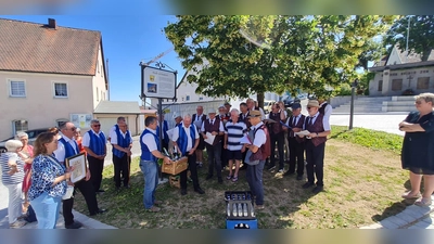 Auf dem Grünsfelder Platz wurde auf Wiedersehen gesagt und gesungen und dazu eine Wegzehrung mit heimischen Produkten für die Heimfahrt mitgeben. (Bild: Josef Varnhold)