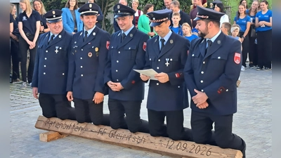 Auf einem Holzbalken kniend, richteten die Gleiritscher Feuerwehrleute ihre feierliche Bitte an die Tännesberger Kameraden und ersuchten sie, die ehrenvolle Patenschaft zu übernehmen. (Bild: Bernhard Zimmet)