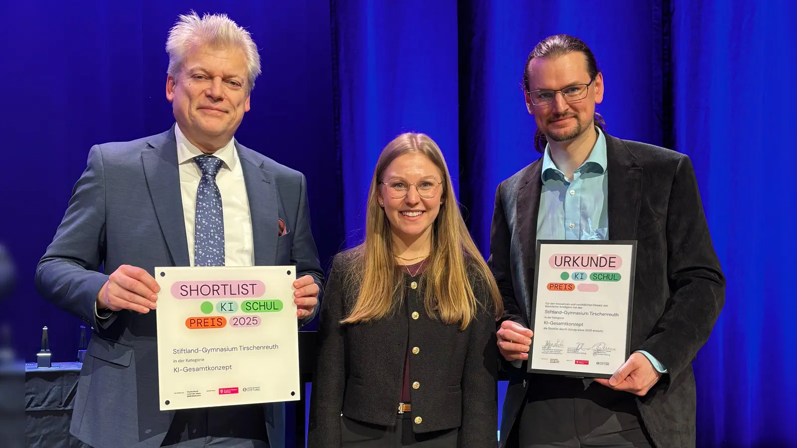 Schulleiter OStD Matthias Weiser, Schülersprecherin Amelie Heyd und stellv. Schulleiter StD Martin Putzlocher erhalten Urkunde und Plakette bei der Preisverleihung des Deutschen KI-Schulpreises in Heilbronn. (Bild: Sebastian Witt)