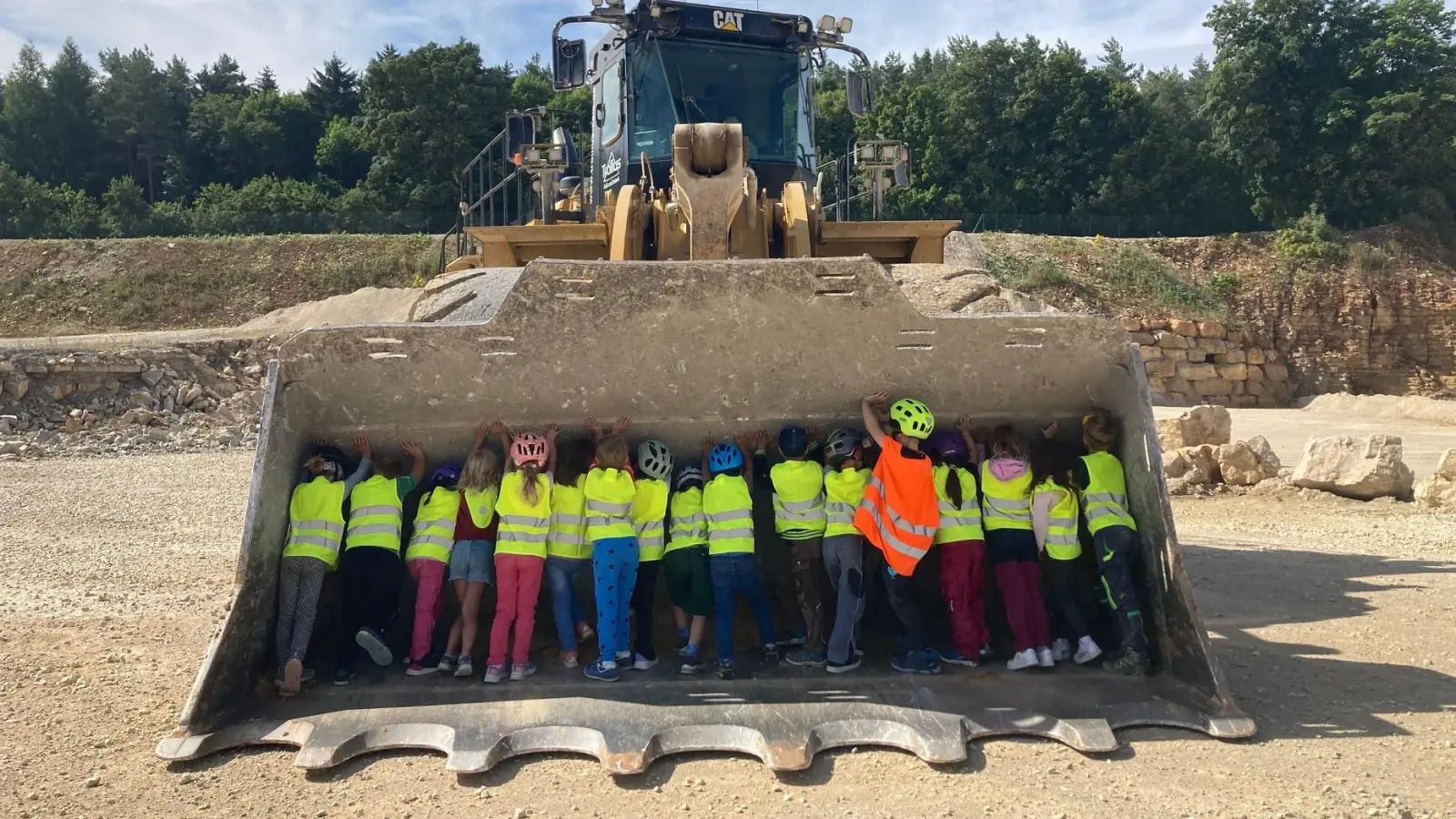 Die Kinder durften das beeindruckende Fahrzeug aus nächster Nähe inspizieren und sogar versuchen, die riesige Laderschaufel „wegzuschieben“ – eine Herausforderung, die mit großem Einsatz gemeistert wurde.  (Bild: Lisa-Marie Traub)