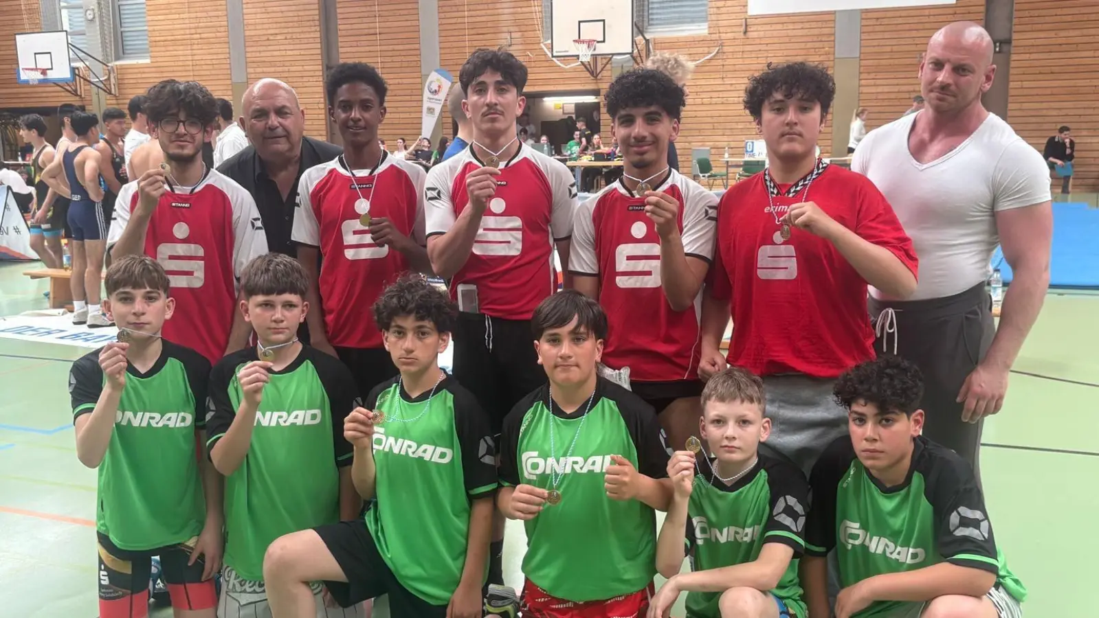 Mit der Goldmedaille als Oberpfalzmeister um den Hals freuten sich die Ringer der beiden Teams der Dreifaltigkeits-Mittelschule (in rot Altersklasse-II und in grün die Altersklasse-III) auch über ihre guten vorderen Mittelfeldplatzierungen bei den Bayerischen Meisterschaften in Weißenburg zusammen mit ihren Lehrern Lukas Braun (1.v.r.) und Thomas Gebele (2.v.l.)  (Bild: Astrid Hollerbach)