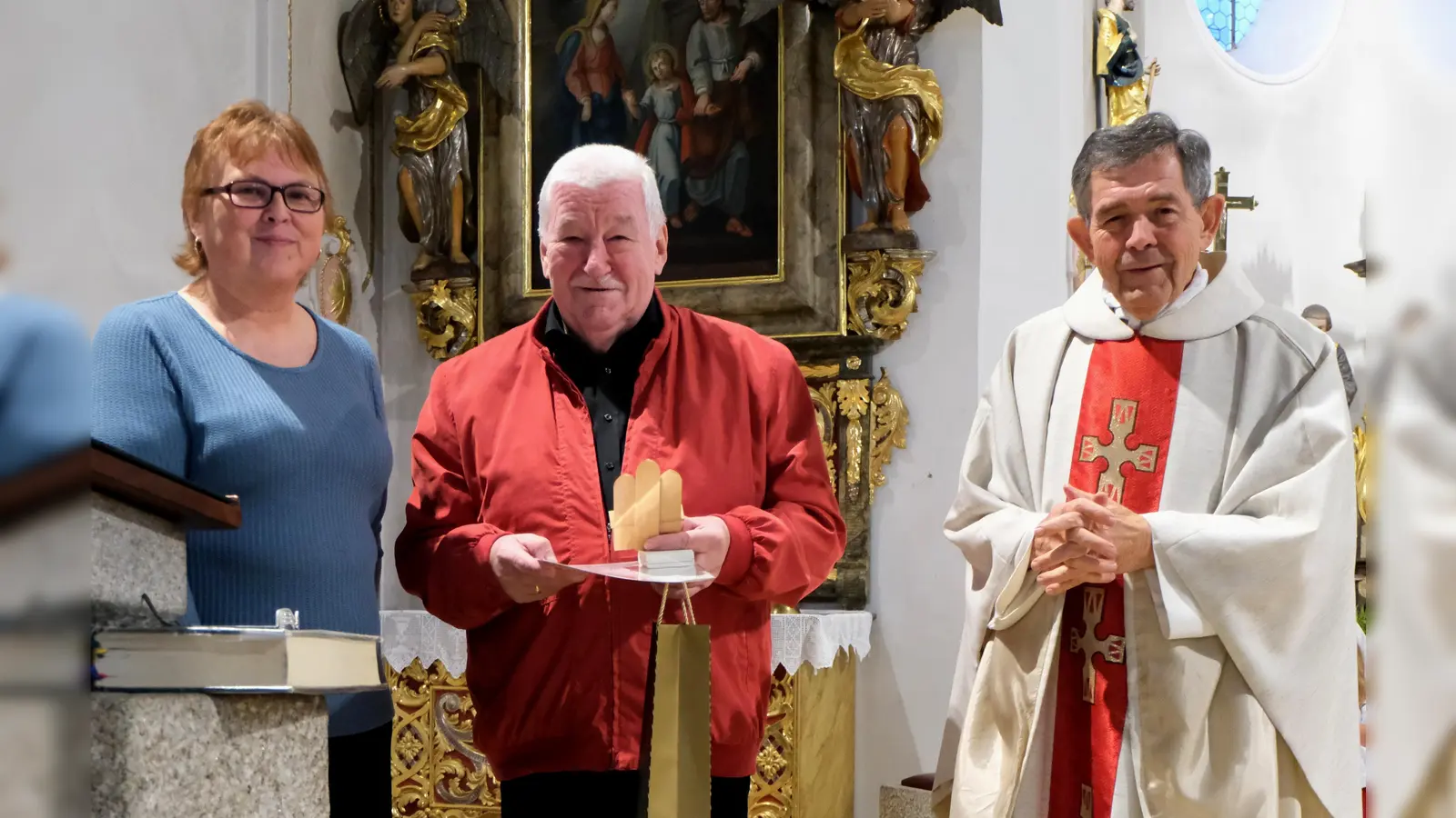 Die Bischofsurkunde, das Ehrenzeichen in Gold für Kirchenmusik, einen im Erzgebirge holzgeschnitzten Engel an der Orgel und eine Flasche Champagner, die Pfarrer Früchtl aus Frankreich mitbrachte, durfte Fröhlich aus der Hand der dankbaren Gratulanten in Empfang nehmen, (Bild: Fred Lehner)