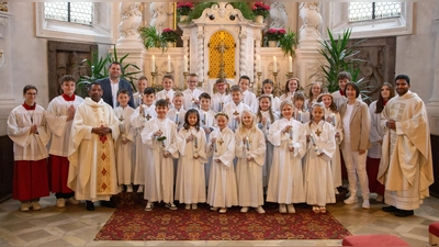 22 Erstkommunionkinder zusammen mit Pfarrer P. Georg Parmampilthadathil, dem Klassenlehrer Christoph Lehner, der Religionslehrerin Reinhilde Bodensteiner, Pfarrvikar P. Joseph Vembadamthara, sowie dem liturgischen Dienst. (Bild: Sandra Dobmeier)