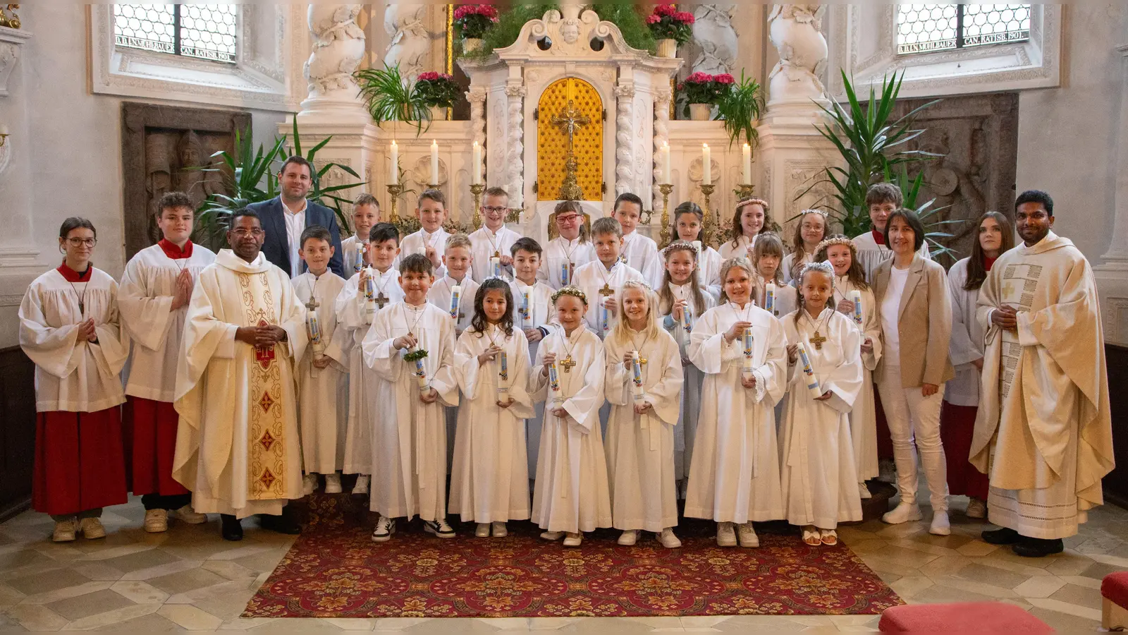 22 Erstkommunionkinder zusammen mit Pfarrer P. Georg Parmampilthadathil, dem Klassenlehrer Christoph Lehner, der Religionslehrerin Reinhilde Bodensteiner, Pfarrvikar P. Joseph Vembadamthara, sowie dem liturgischen Dienst. (Bild: Sandra Dobmeier)