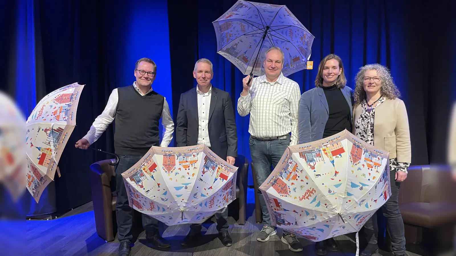 Ein Regenschirm als Symbol für Sulzbach-Rosenberg – und für Zukunftsideen: Die Diskussionsrunde im Capitol, moderiert von der Bürgermeisterkandidatin, mit dem augenzwinkernden Hinweis, dass in kommenden Modellen vielleicht auch TTZ und Maxhütten-Campus ihren Platz finden. V.l. Frederik Betsch und Professor Matthias Franke (FRAUNHOFER UMSICHT), Stadtrat und Unternehmer Mike Schulz, von den GRÜNEN MdL Laura Weber und Bürgermeisterkandidatin Yvonne Rösel. (Bild: Yvonne Rösel)