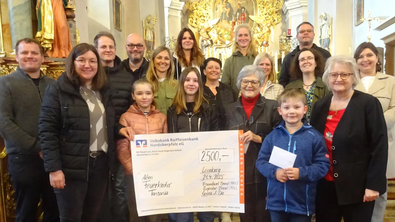 Spendenübergabe an die „Feuerkinder“. Dr. Annemarie Schraml (Mitte), Chorleiterin Angela Burger (links vorne) und Marianne Maurer (rechts) im Kreis des Chores. (Bild: Alfons Prechtl)