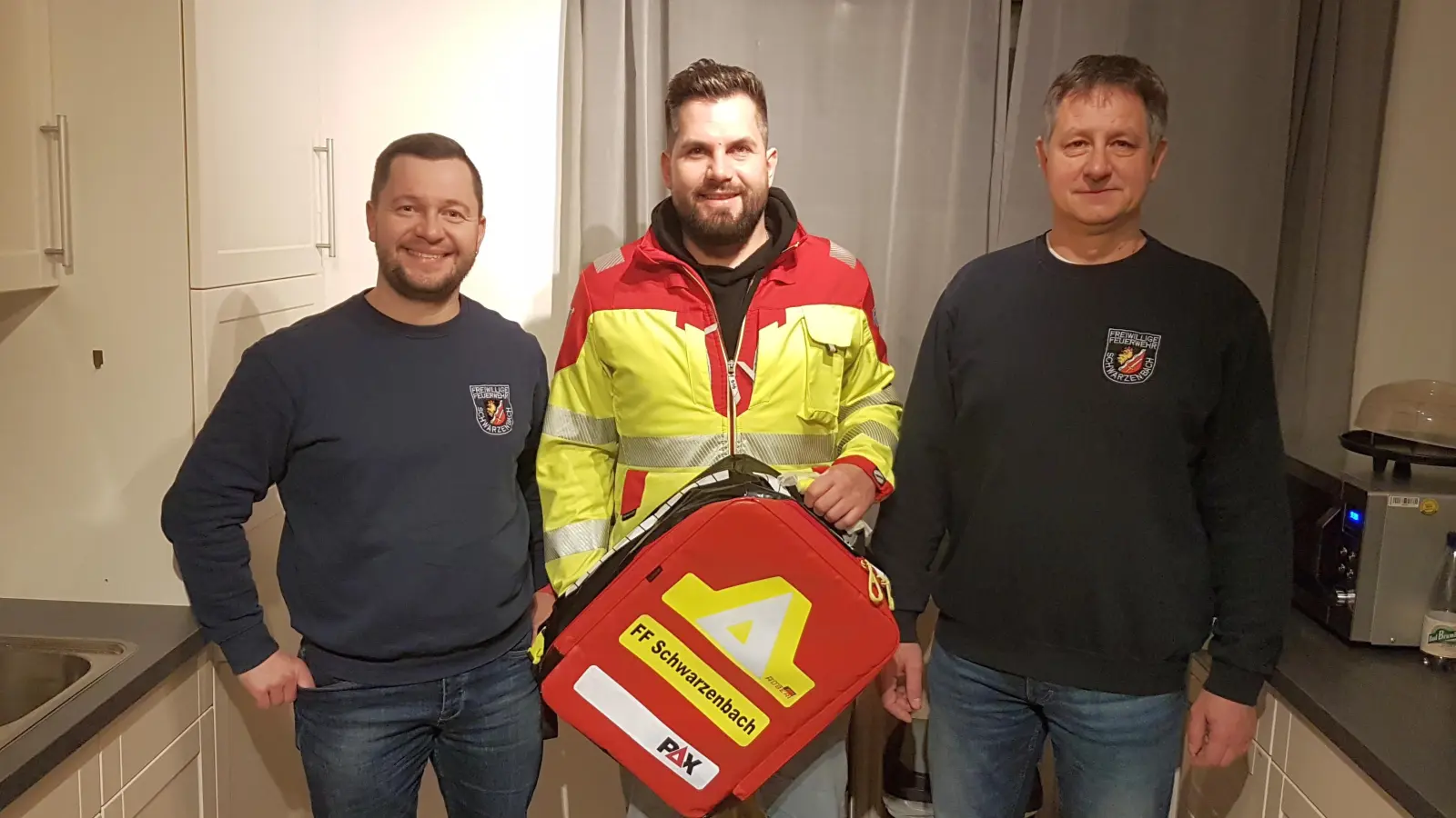 Übergabe des neuen Rettungsrucksacks von RKT-Regionalleiter Südbayern, Tim Christen (Mitte) an Kommandanten Bernd Przetak (rechts) und Vorsitzenden Markus Pöllath (links) von der Schwarzenbacher Feuerwehr. (Bild: Thorsten Hallmann)