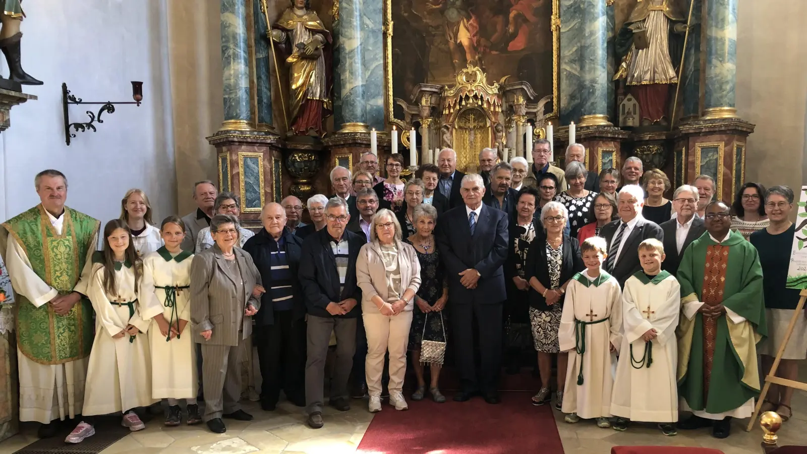 Erinnerungsbild der Ehejubilare 2026 vor dem Hochalter in Schlicht mit den Ministranten, den Geistlichen Alfons Schöpf (li.). Hruday Madanu und den PGR-Sprecherinnen Sabine Kederer und Monika Krieger (alle re.) (Bild: ct)