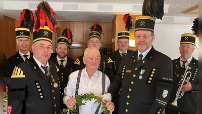v.l. 2.Vorstand Martin Kernl, Jubilar Richard „Pömerer” Fuchs und 1.Vorstand Armin Kraus gratulierten mit einem Geschenkkorb. Im Hintergrund eine Abordnung der Bergknappenkapelle unter der Leitung von Siegfried Meier (hi.Mitte). (Bild: Karin Kraus)