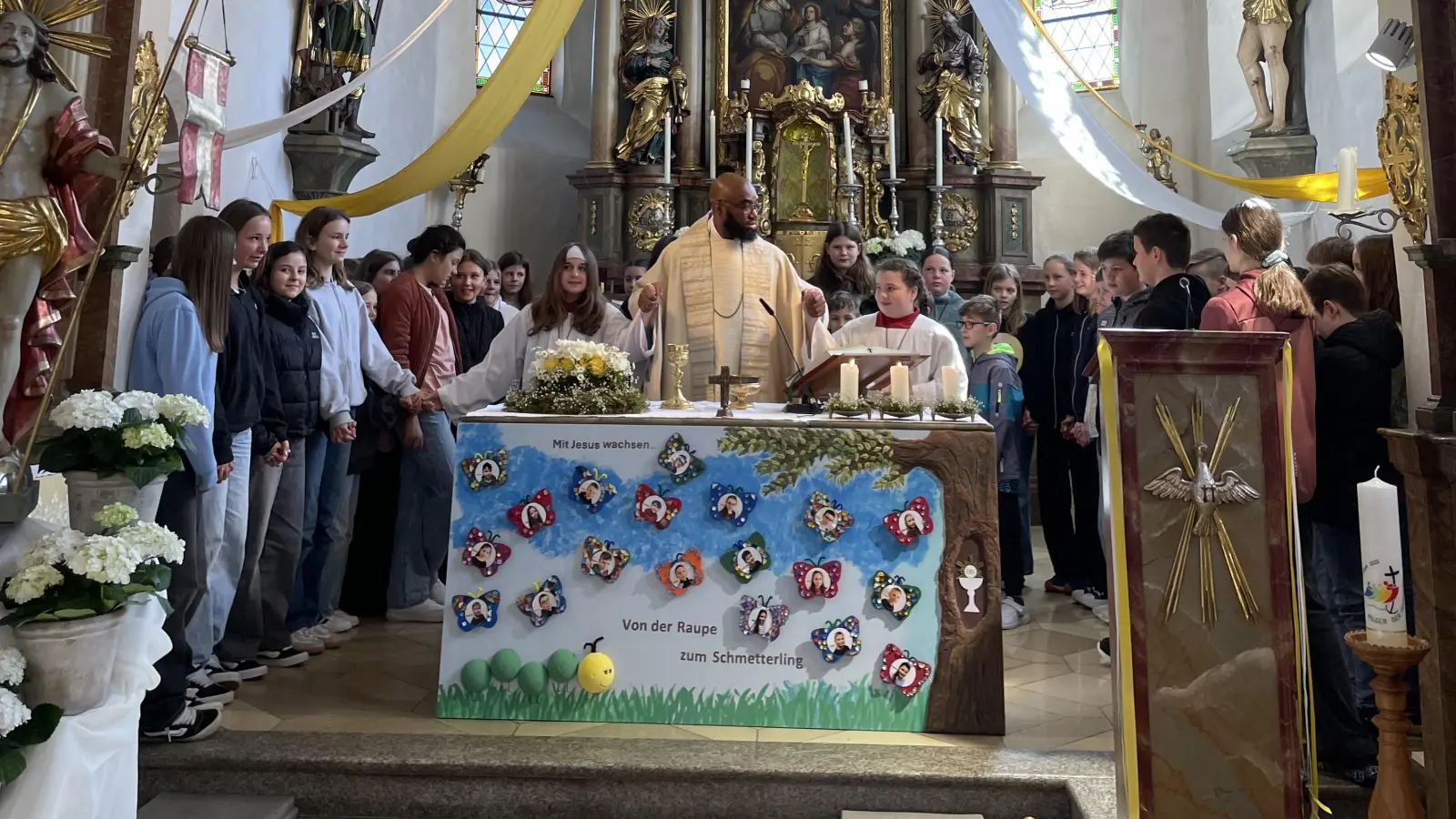 Alle Firmlinge mit Pfarrvikar Bonaventure Ukatu versammelt um den Altar beim Vaterunser Singen. (Bild: Maria Schlögl)