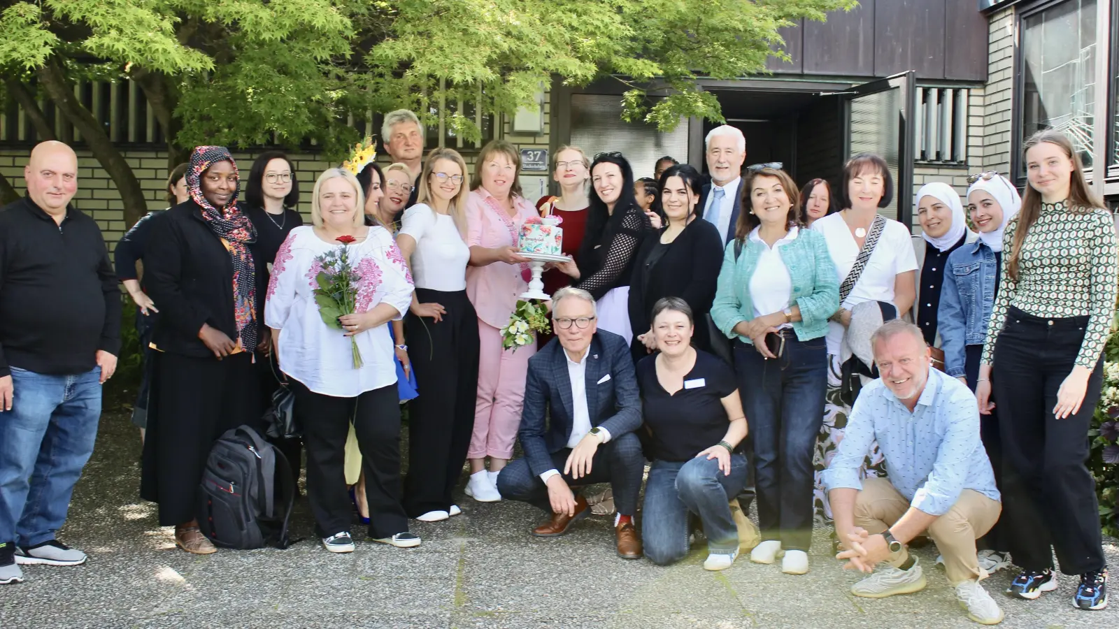 Feierliche Bewirtung mit Festtagstorte vor dem evang. Gemeindezentrum mit Stadträt:innen: Reinhold Wildenauer (3. Bürgermeister) sitzt vorne, Sema Tasali-Stoll (SPD) vorne rechts, daneben rechts Brigitte Schwarz (SPD), im Hintergrund rechts Reinhard Meier (Bürgerliste). (Bild: Nataliia Branopolska )