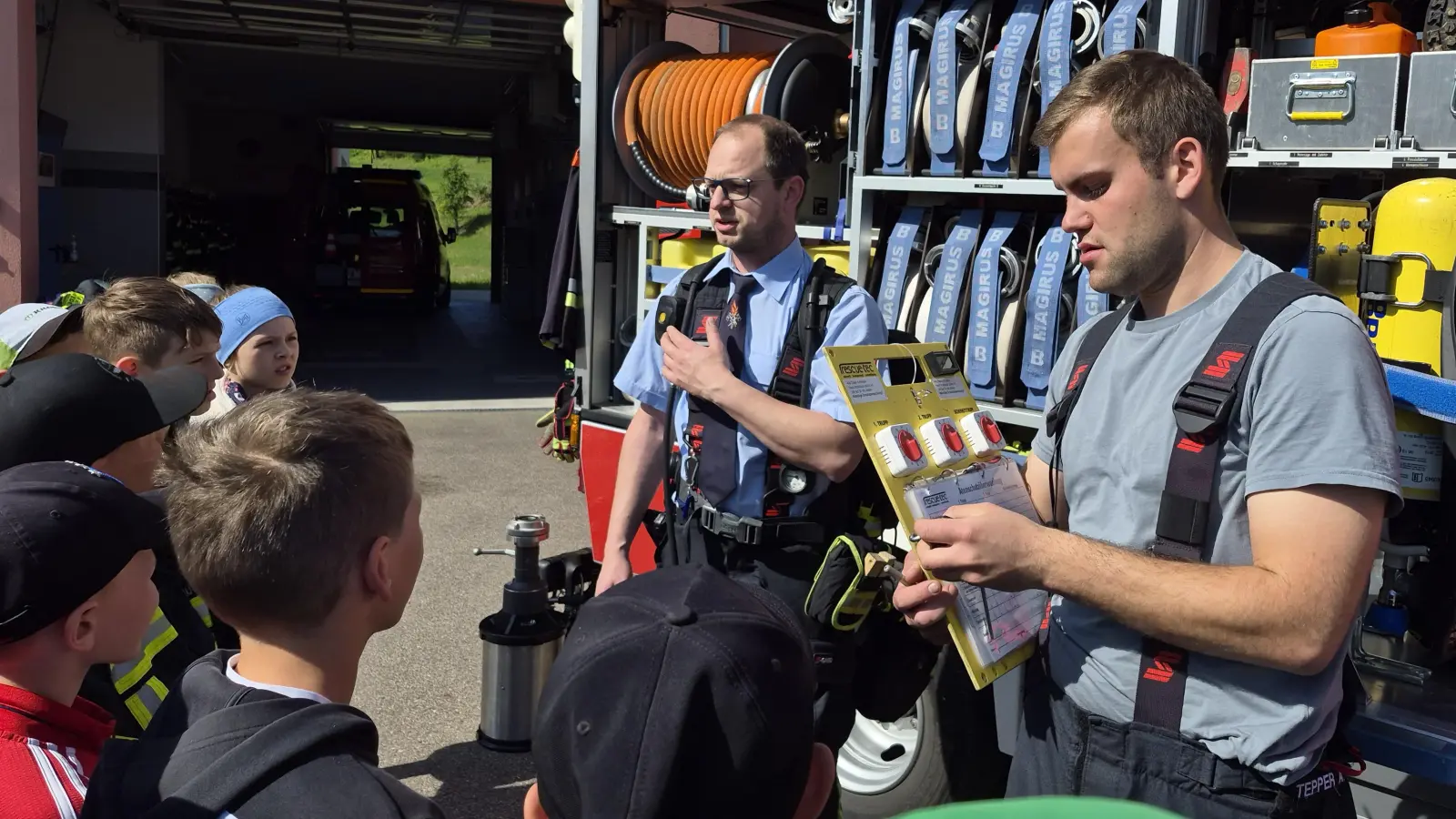 Dominik Schießlbauer und Andreas Stepper erklärten den Kindern, wie Feuerwehrleute bei einem Brandeinsatz mit Atemschutz im Gefahrenbereich von außen überwacht werden. (Bild: Ortrud Sperl)