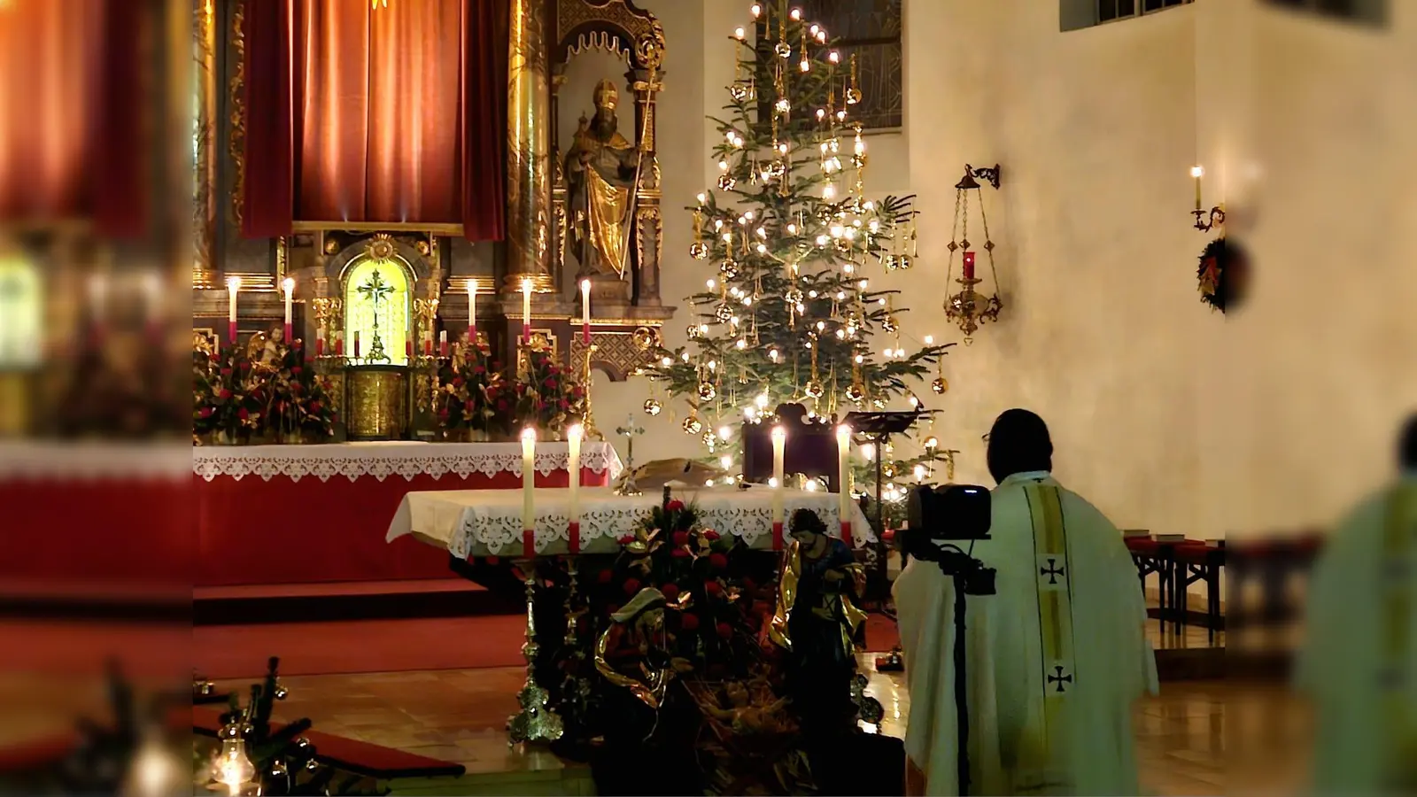 Pfarrvikar Robert vor dem festlich geschmückten Altar und der Krippe zum Abschluss der Christmette. (Bild: Beate Suttner)