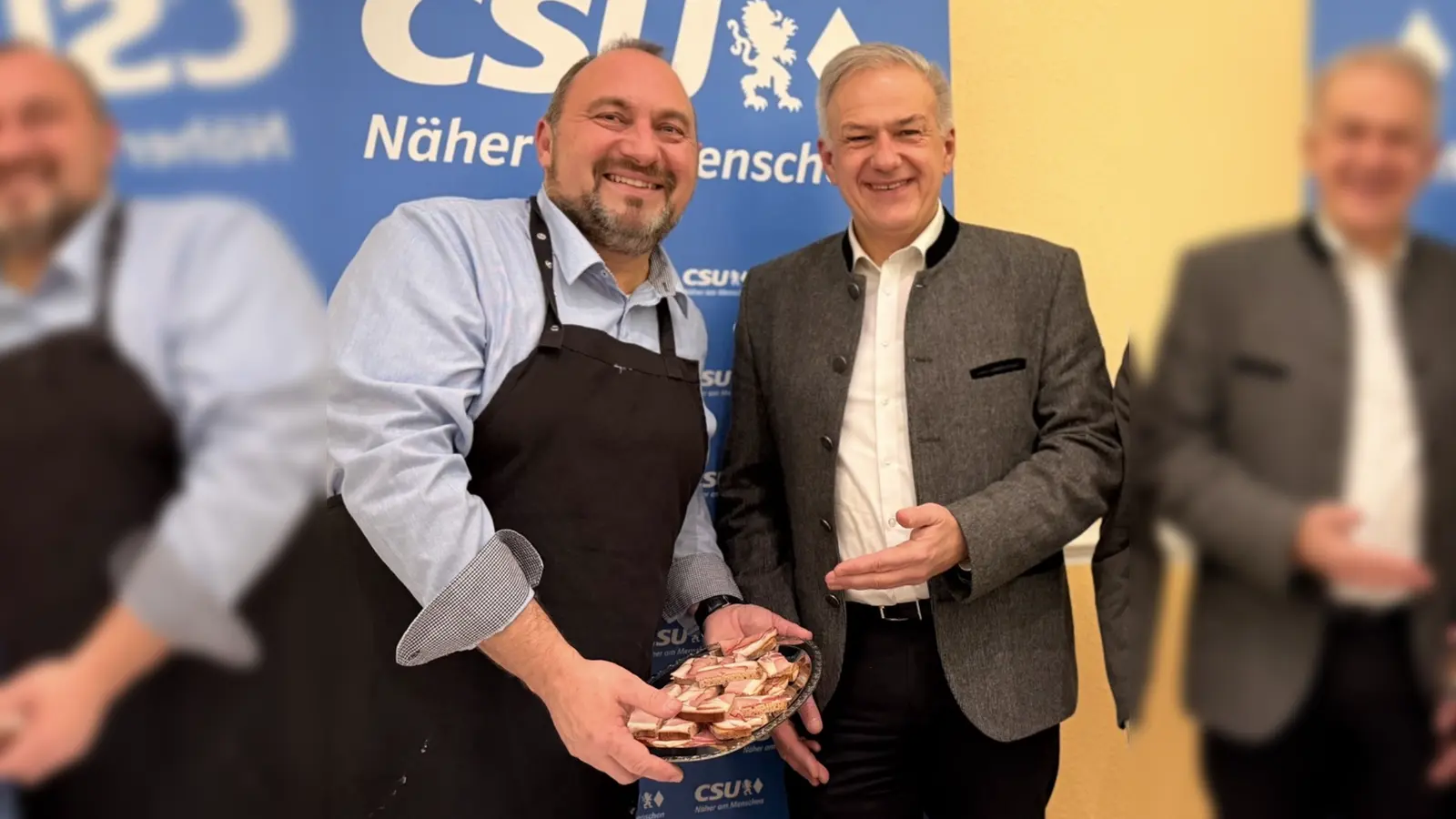 Auch dem Landrat Roland Grillmeier bietet Bürgermeisterkandidat Oliver Becher eine Stärkung an. (Bild: Johannes Koller)