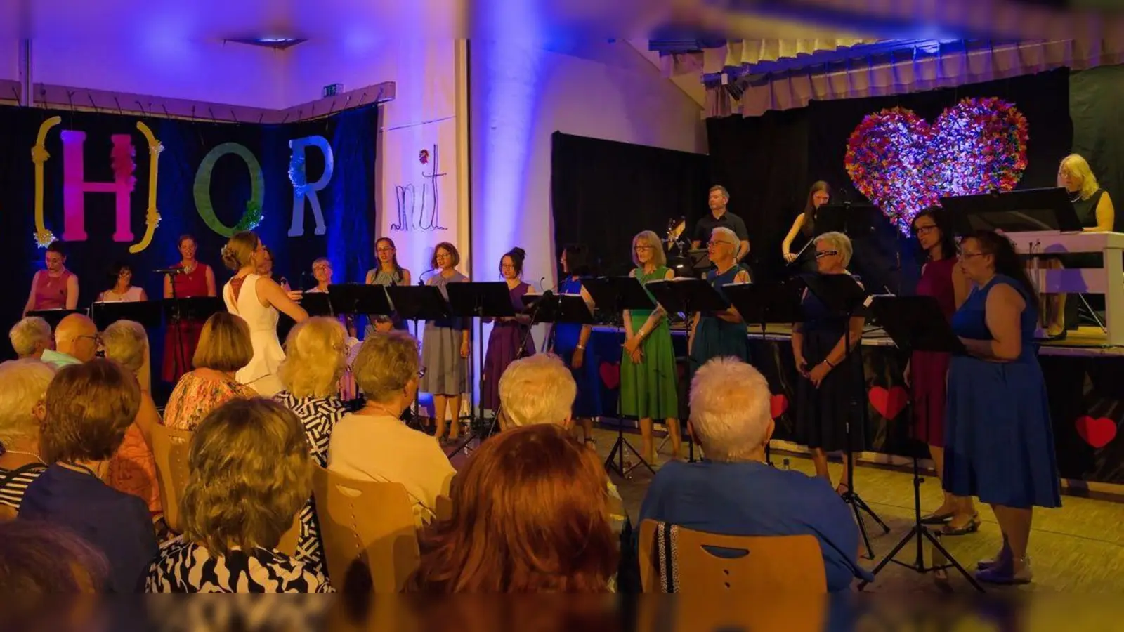14 Sängerinnen mit der Chorleitung Ulrike Straub legten schon zu Beginn einen musikalischen Farbmantel aus. Die dreiköpfige Band, bestehend aus Irina Hermann (Klavier), Elisabeth Haas (Violine) und Florian Beer (Schlagzeug), holten dabei alle musikalischen Klangfarben aus ihren Instrumenten hervor, die sich finden ließen. (Bild: Elke Scheidler)