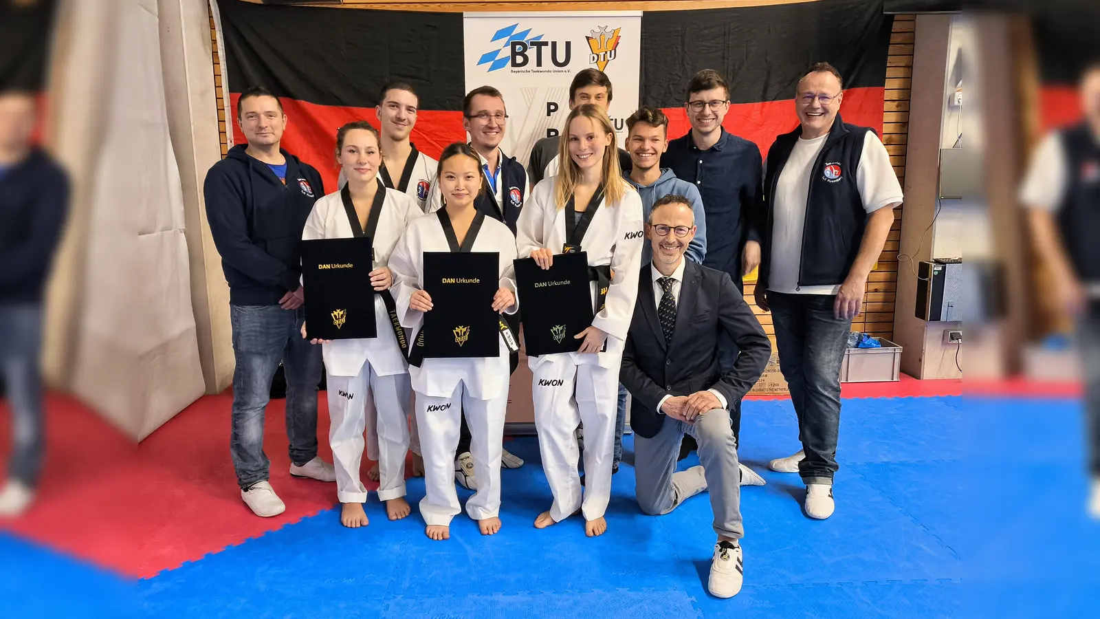 Das Bild zeigt die drei Prüflinge mit den Trainern und den mitgereisten Unterstützern (Bild: Jürgen Brand)