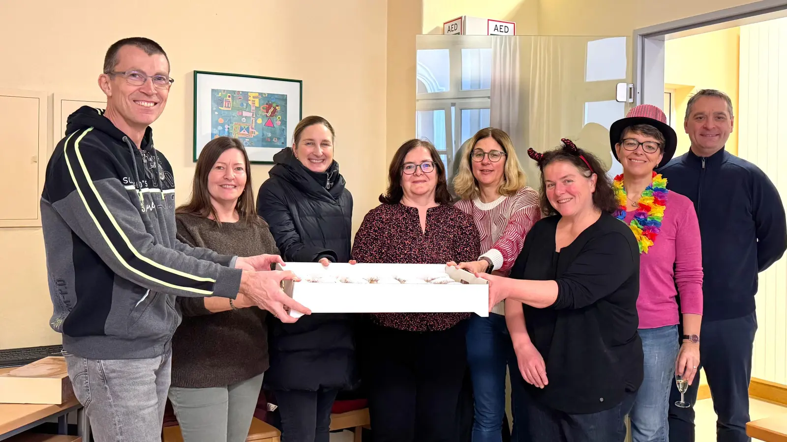 Organisator Michael Luig, 1. Vorsitzender des DJDS-Fördervereins (ganz links), präsentiert zusammen mit Elternbeiräten und Lehrkräften einen Karton der leckeren Krapfen, die am Unsinnigen Donnerstag in Amberg und Umgebung ausgeliefert wurden. (Bild: Michael Luig)