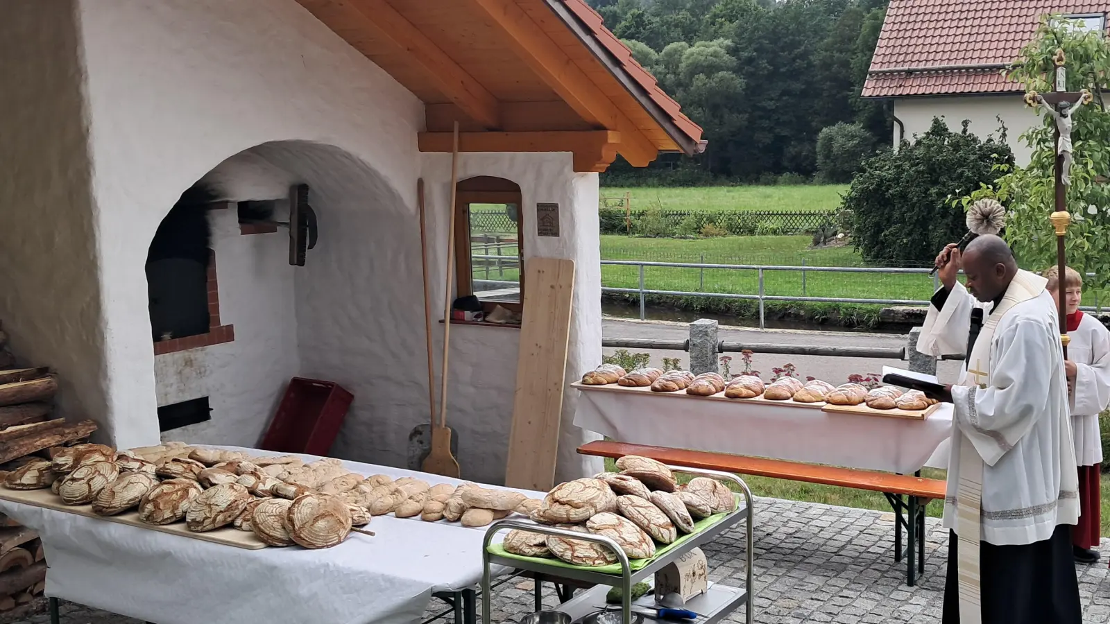 Pfarrvikar Kenneth Onuoha spendet den Segen für den Holzbackofen. (Bild: Michaela Müller)