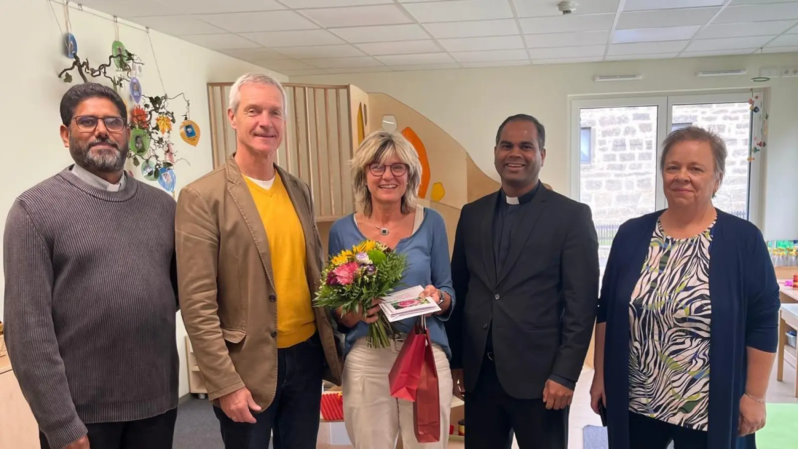 Pfarrvikar Dr. John Palathinkal Kuriako (1.v.l.), Kirchenpfleger Josef Völkl (2.v.l.), Pfarrer John Subash Vincent ( 2.v.r.) und die Kindergartenleiterin Christine Schwepesch (1.v.r.) gratulieren Frau Manuela Landgraf (mitte) zu ihrem außergewöhnlichen 40jährigen Dienstjubiläum im Kindergarten St. Franziskus. (Bild: Christina Rosner)