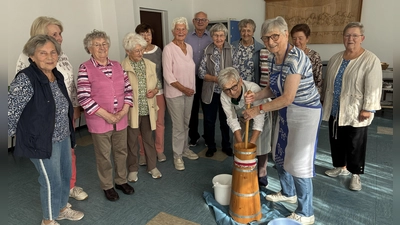 Erni Liebwein (stehend) und Marianne Reichl am Butterfass, umringt von einigen interessierten Senioren und von Prälat Johannes Neumüller (Bild: Margit Konze)