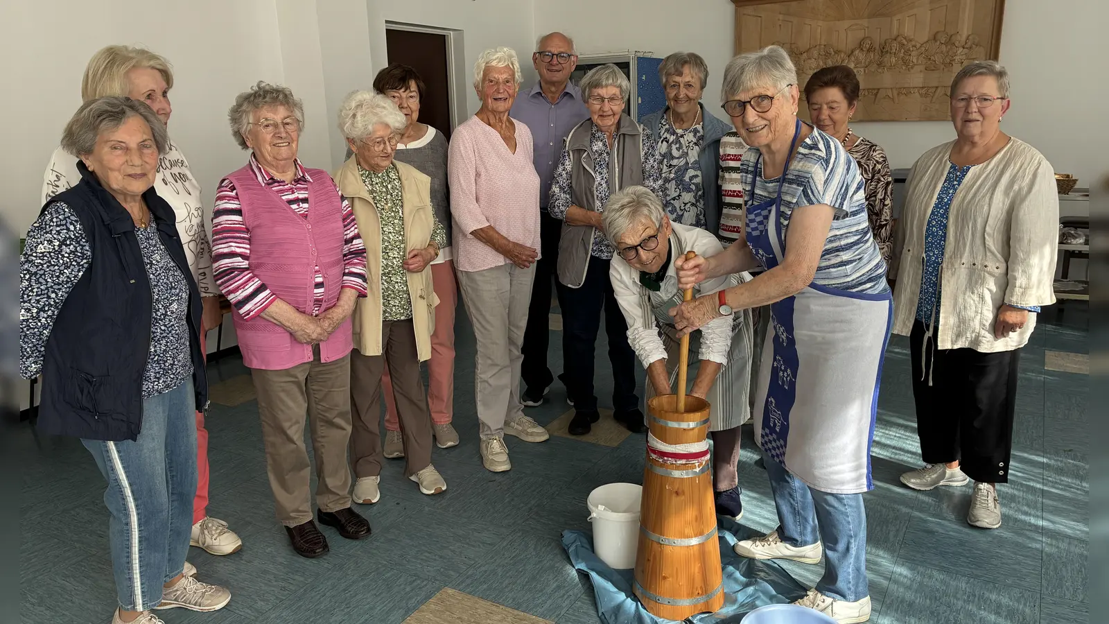 Erni Liebwein (stehend) und Marianne Reichl am Butterfass, umringt von einigen interessierten Senioren und von Prälat Johannes Neumüller (Bild: Margit Konze)
