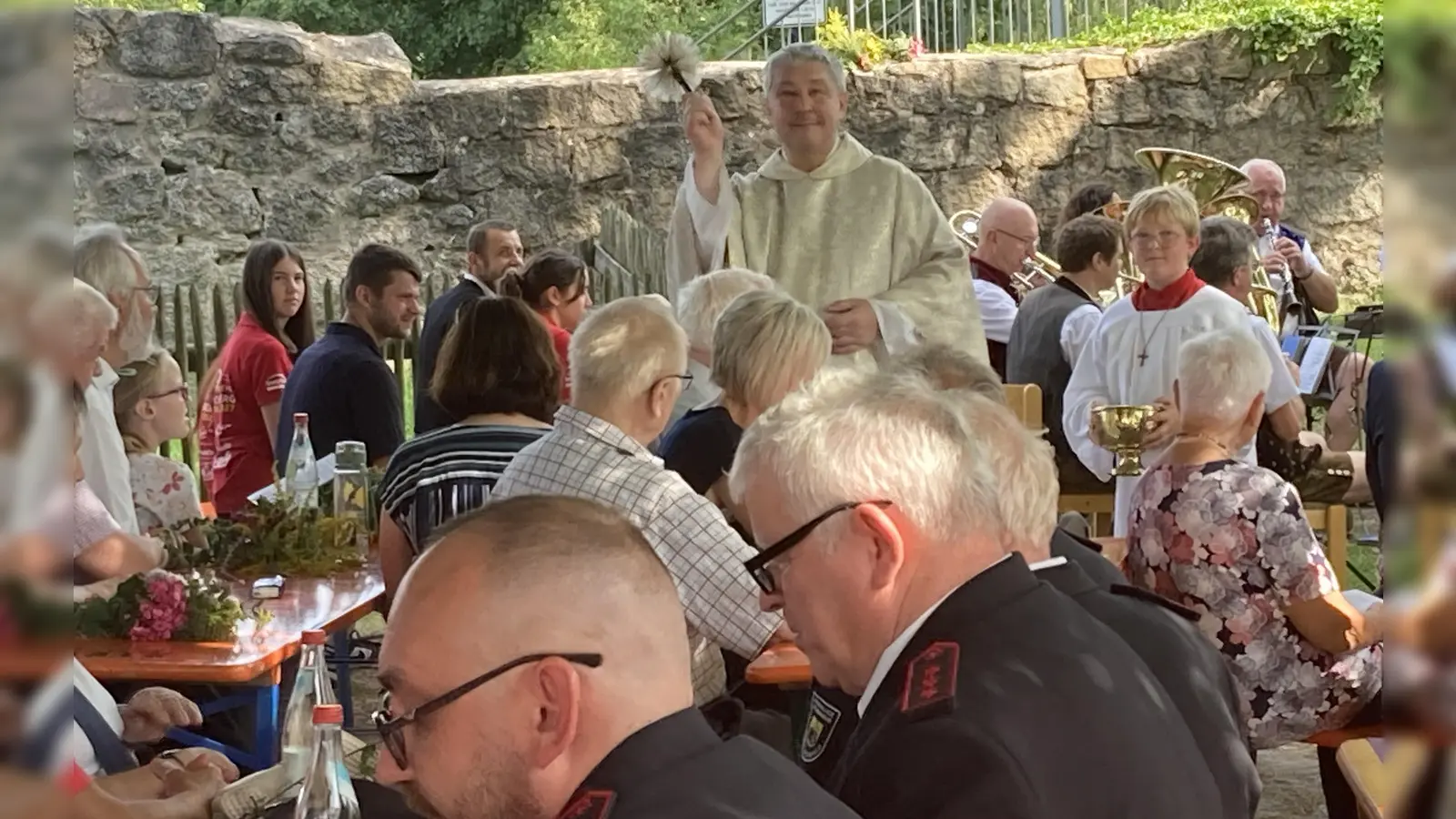 Pfarrer Adam Niecieki geht mit Ministranten Timo durch die Reihen um die Kräuterbüschel mit Weihwasser zu segnen. (Bild: Sieglinde Schärtl)
