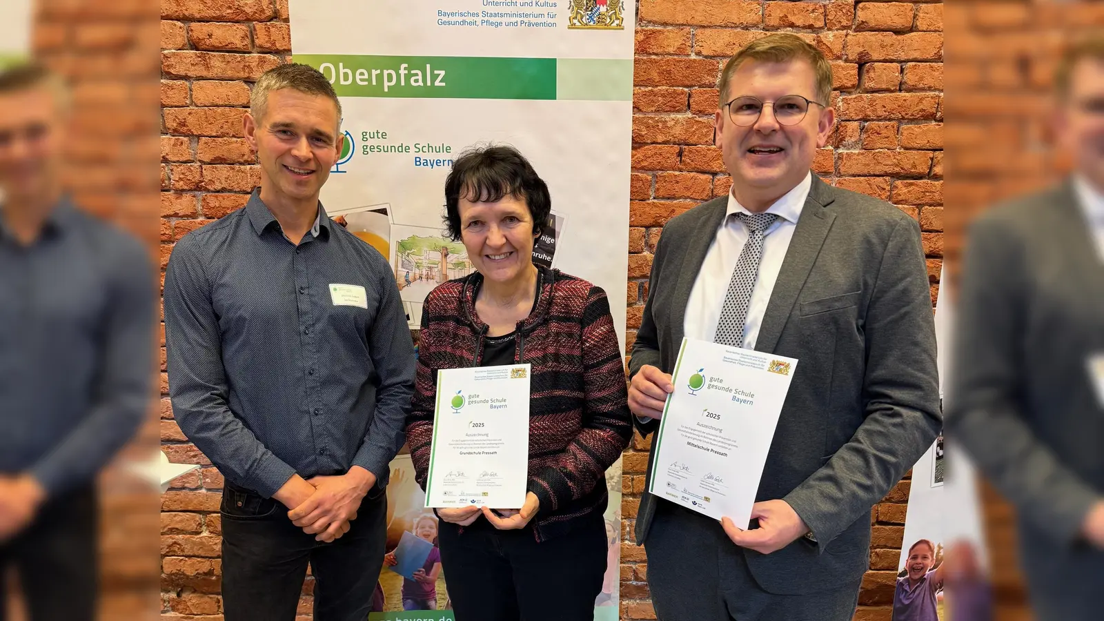 Die Grund- und Mittelschule Pressath wurde als „Gute gesunde Schule“ ausgezeichnet: Moderator Dominik Eckert, Ulrike Neiser und Holger Popp mit den Urkunden (Bild: Matthias Balk )